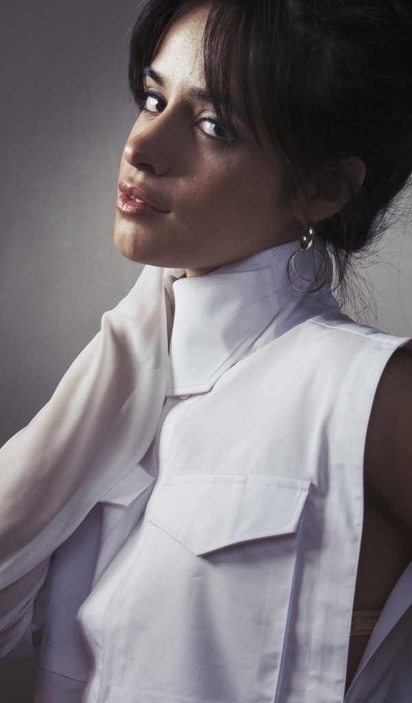 Молодая певица Камила Кабельо в белом костюме у стены