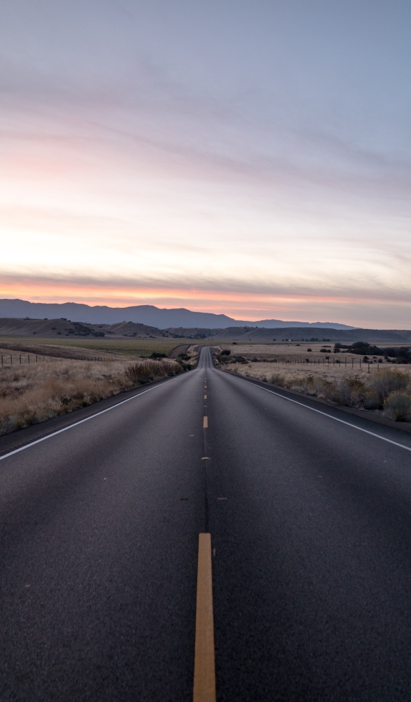 Асфальтная дорога уходит вдаль на фоне неба