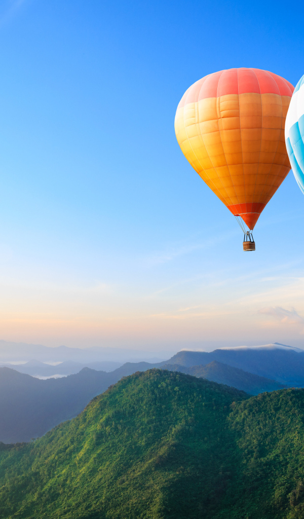 Большие воздушные шары в голубом небе над зелеными холмами