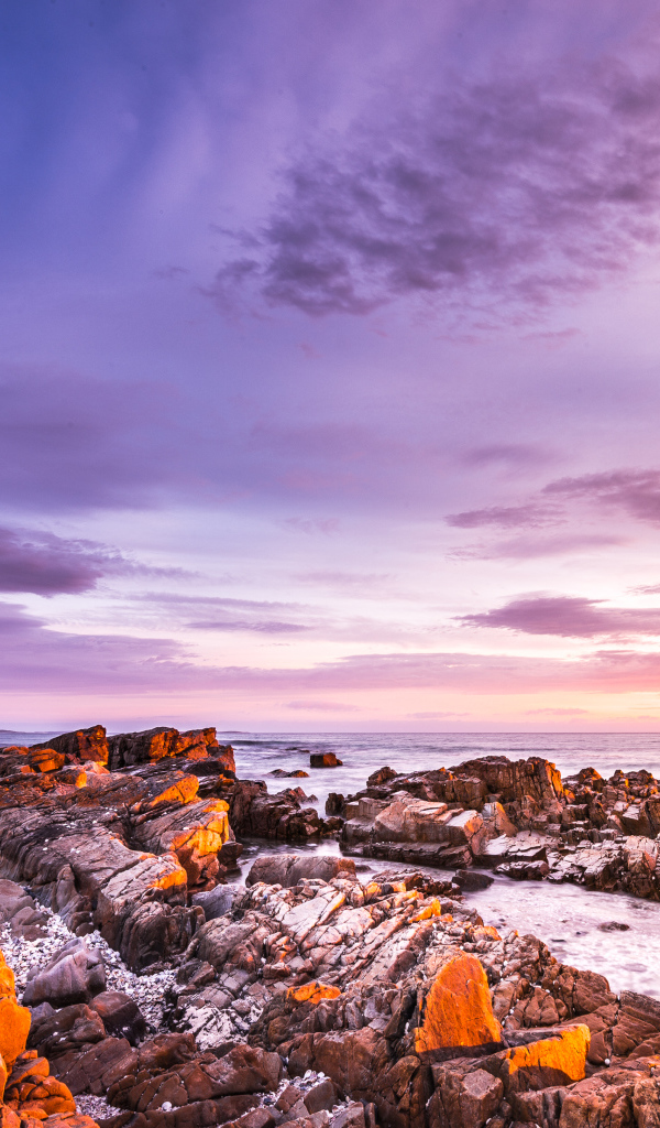 Каменный берег в море на закате солнца