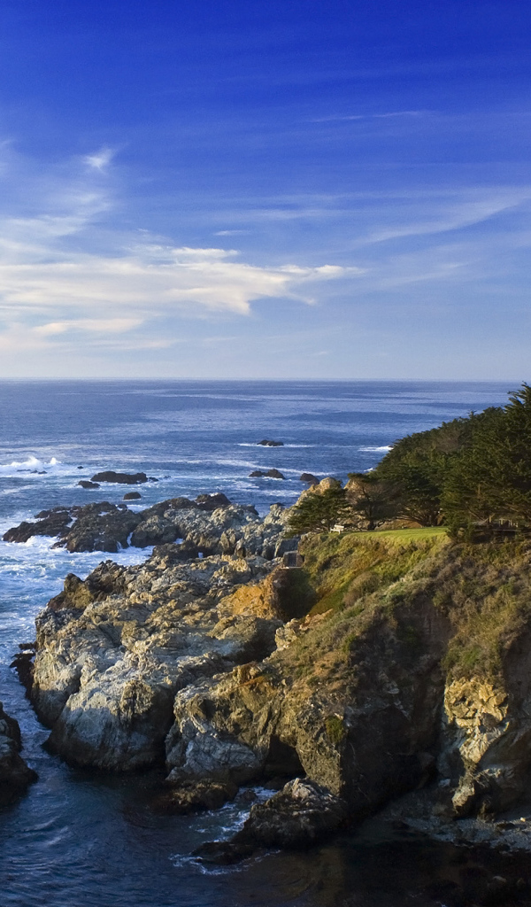 Каменные скалы береговой линии в океане под голубым небом