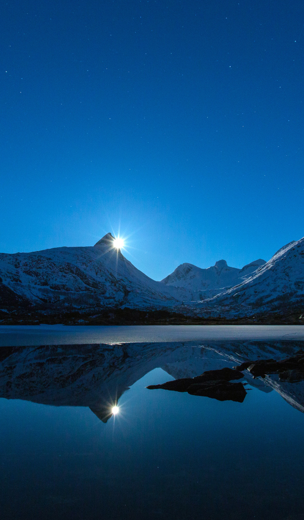 Луна и заснеженные горы отражаются в воде 