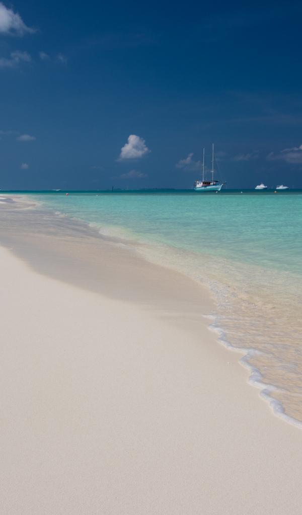 Спокойные волны на белом горячем песке под голубым небом