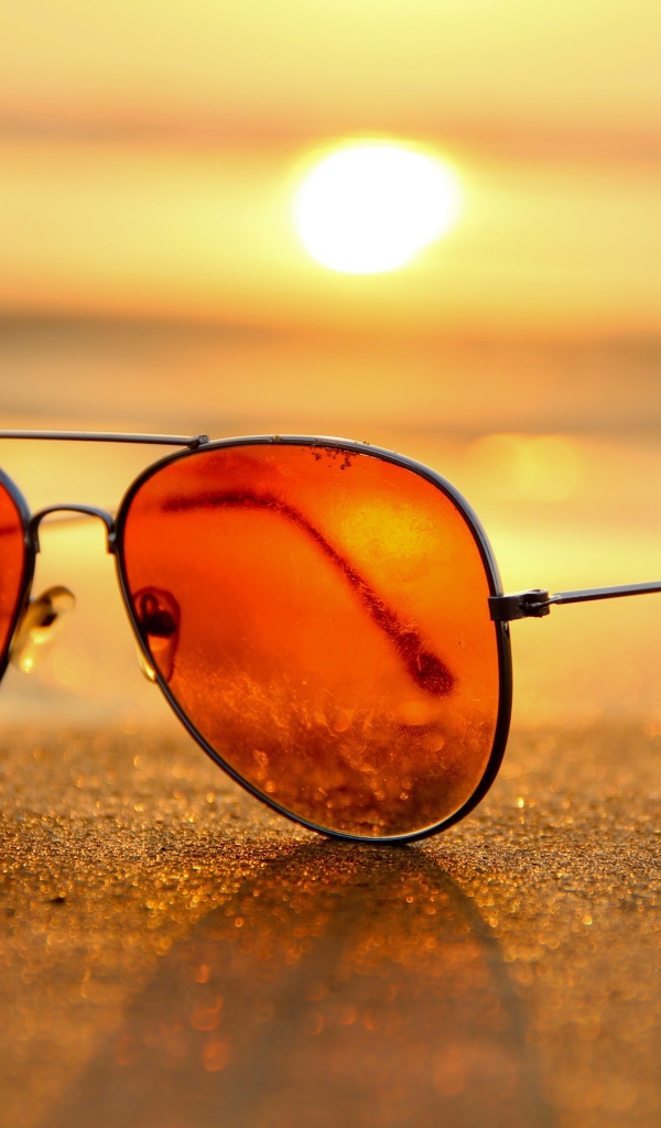 Солнечные очки лежат на горячем морском песке