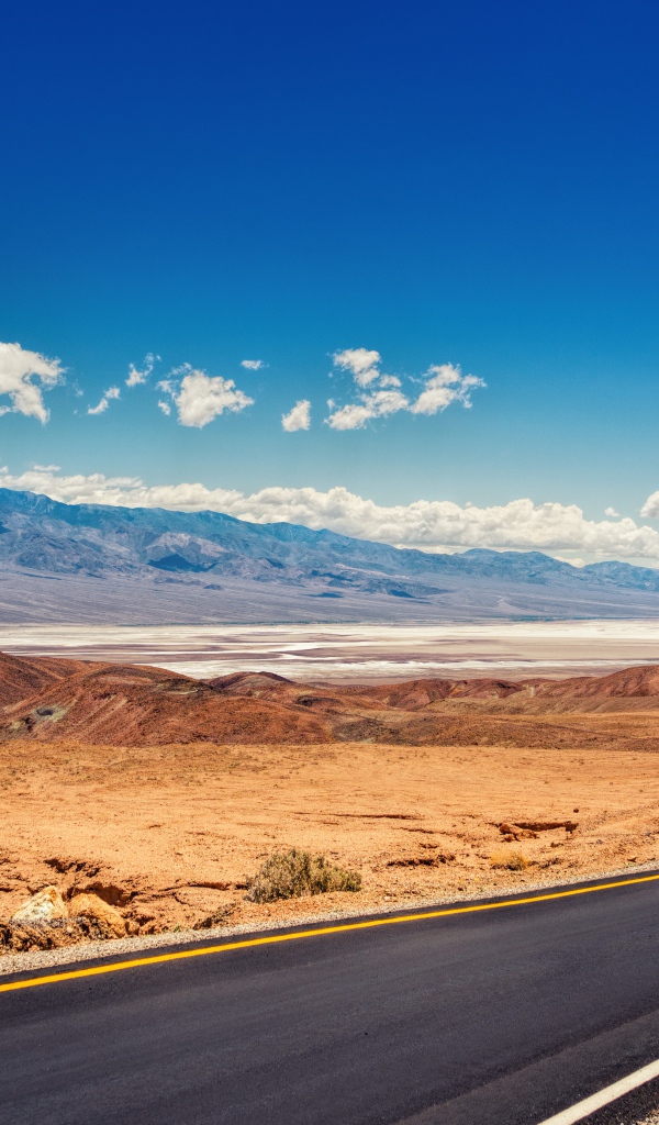 Дорога в пустыне под красивым голубым небом с белыми облаками
