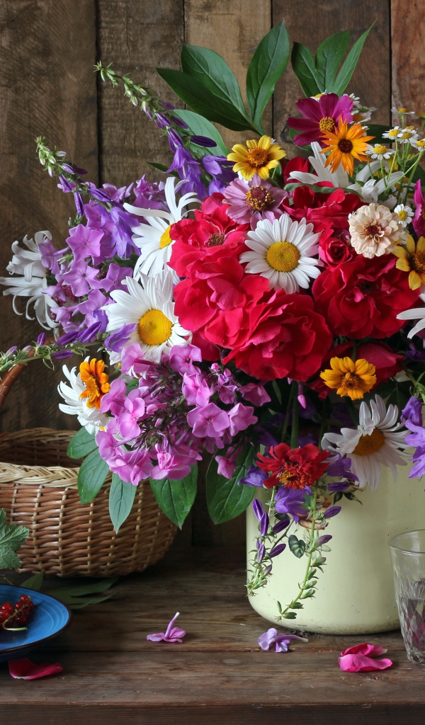 Красивый букет стоит на  столе с красной смородиной