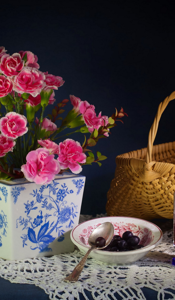 Букет гвоздик в красивой вазе на столе с корзиной и соком