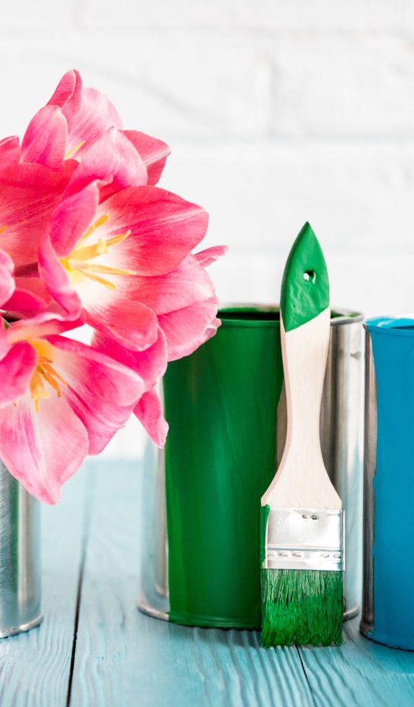 Букет розовых тюльпанов на столе с банками краски и кисточками