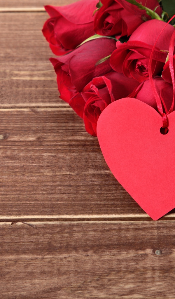 Букет красных роз на деревянном столе с красным сердцем