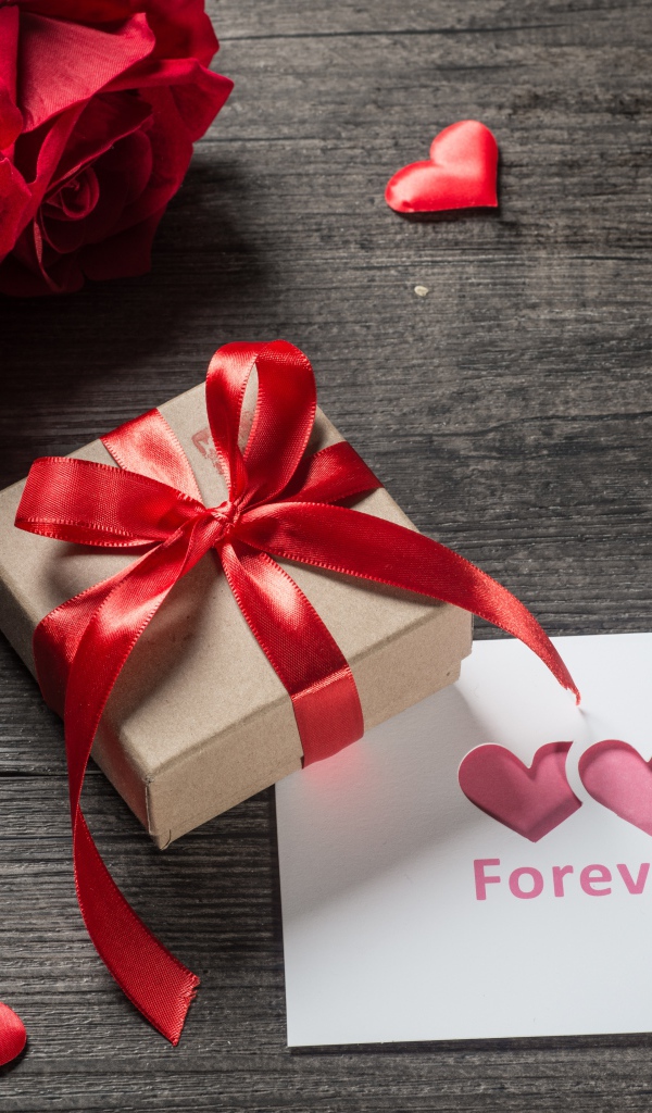 Букет красных роз с подарком и открыткой на столе