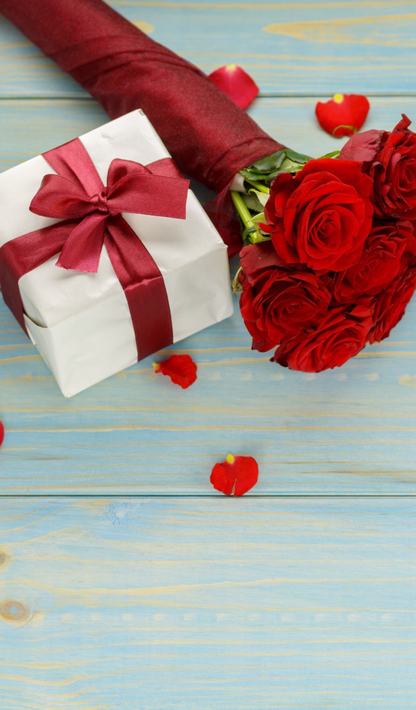 Букет красных роз с подарками на столе