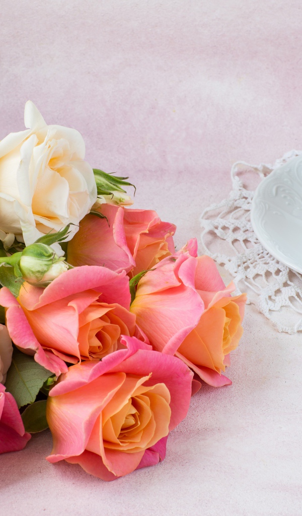 Красивый букет нежных роз на столе с чашкой чая