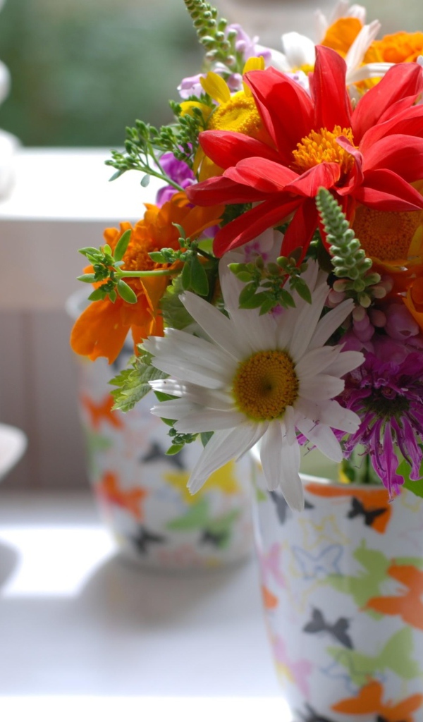 Букет разноцветных  садовых цветов в вазе на столе 