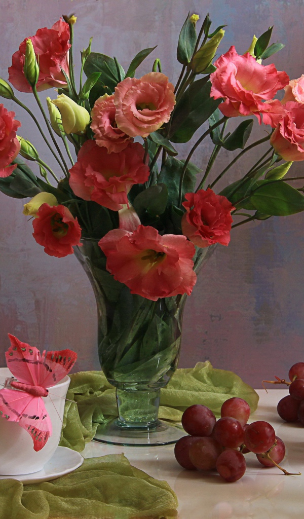 Букет розовых цветов эустомы на столе с виноградом