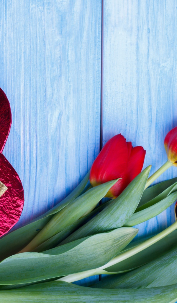 Букет красных тюльпанов на синем фоне с подарком в форме сердца