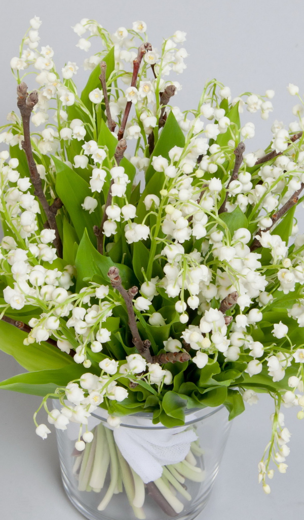 Букет белых ландышей в вазе на сером фоне