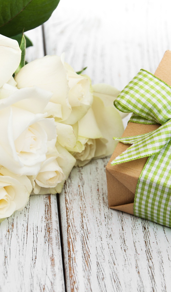 Букет белых роз на столе с подарком