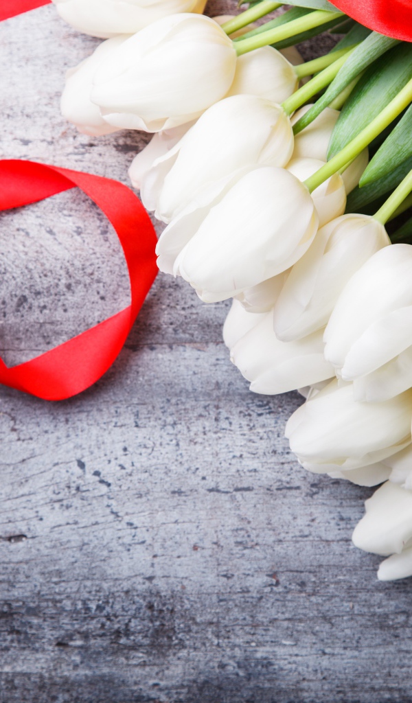 Букет белых тюльпанов с красным бантом на сером столе