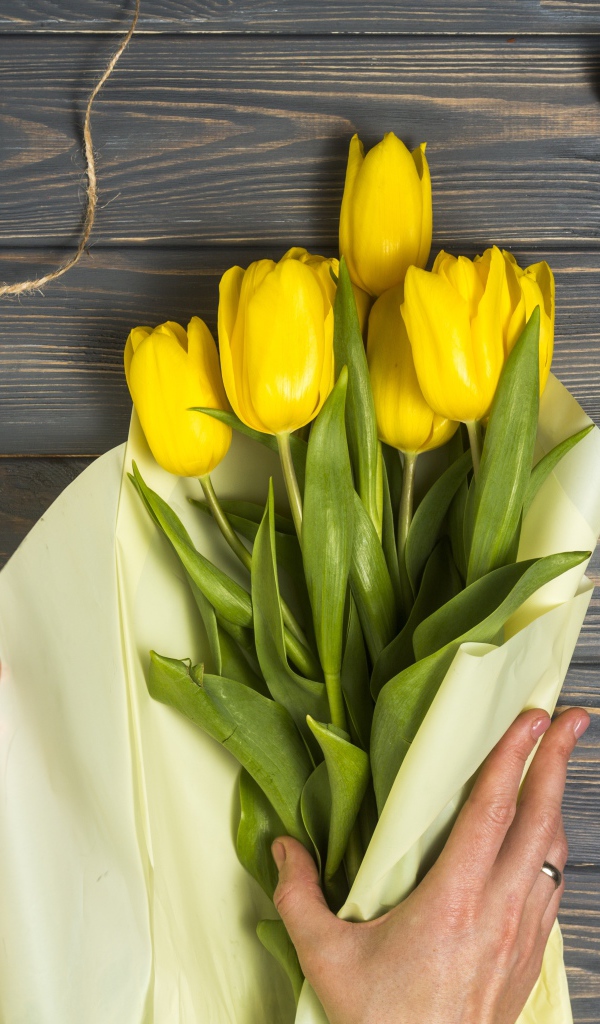 Букет желтых тюльпанов заворачивают в бумагу