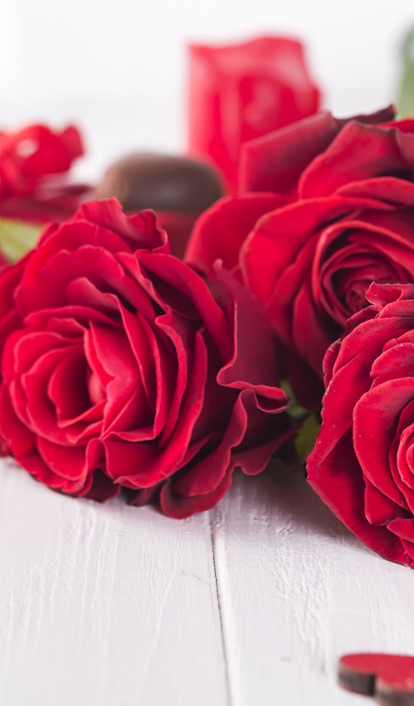 Три красивые красные розы на столе с конфетами