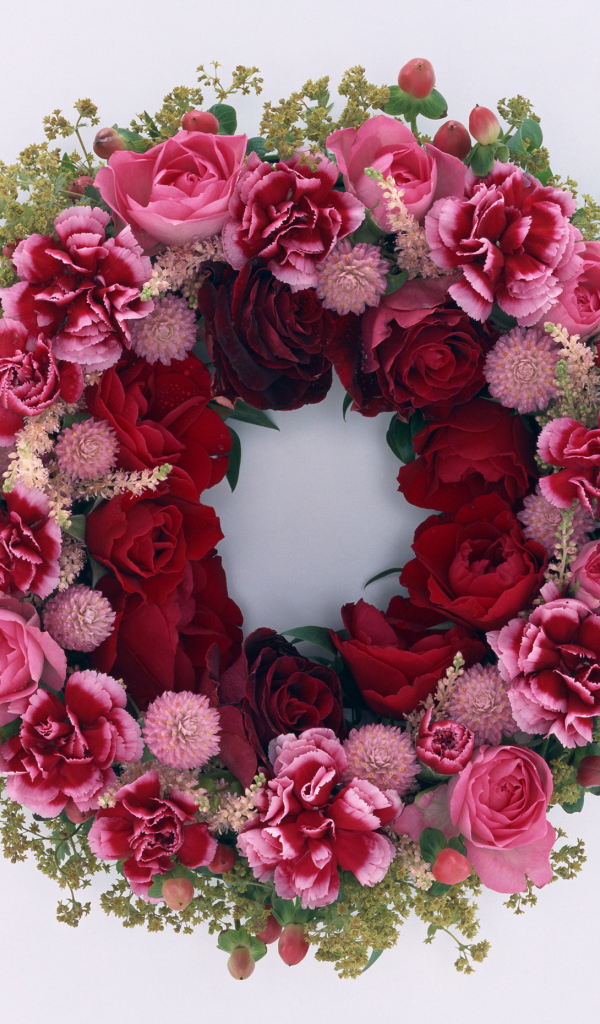 Венок и красных роз с цветами гвоздики на сером фоне