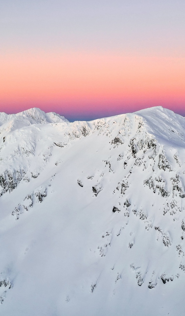 Красивые заснеженные вершины горы на фоне розового неба