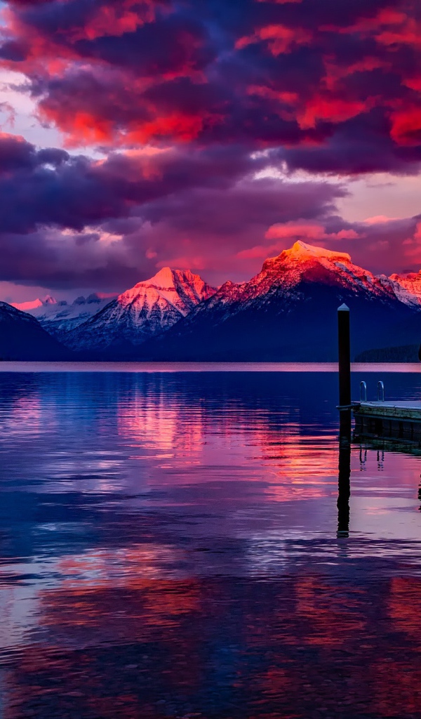 Красивый закат в небе над вершинами заснеженных гор у озера