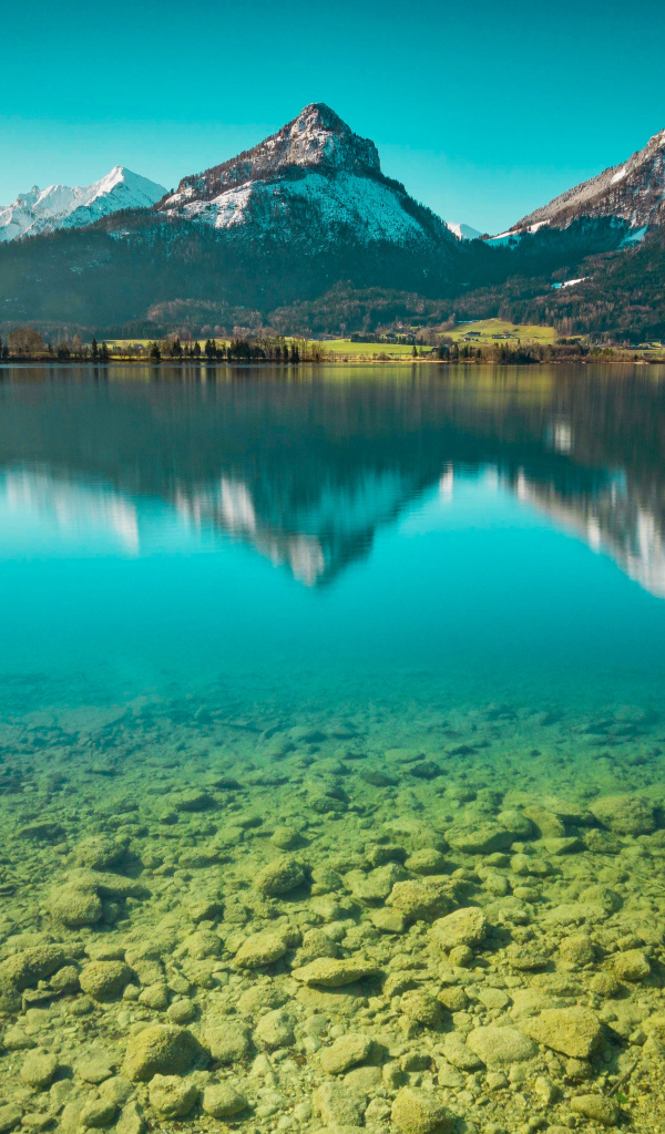 Заснеженные горы отражаются в чистой воде озера 