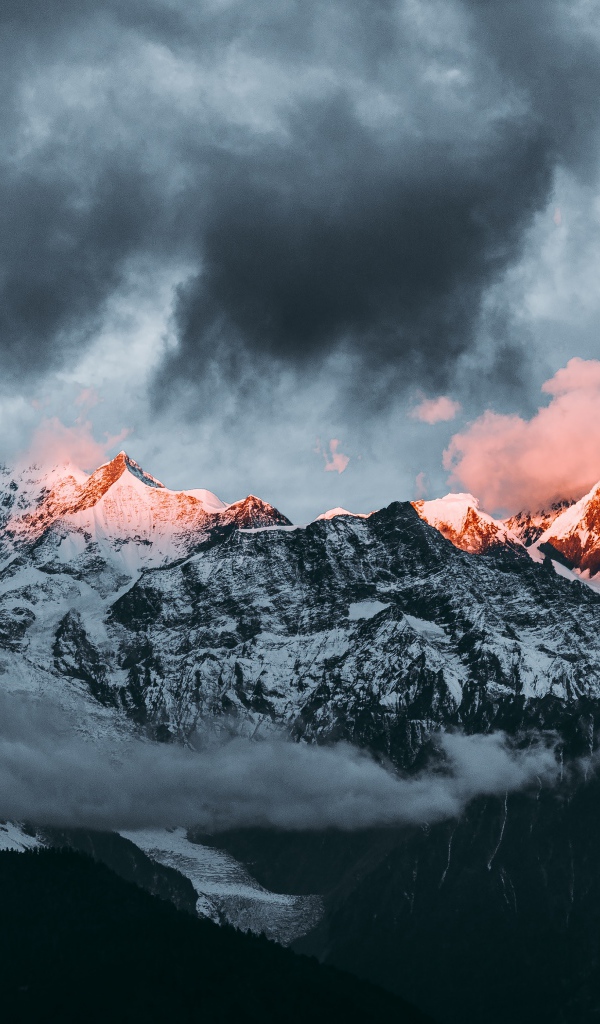 Солнце на рассвете освещает вершины заснеженных гор 