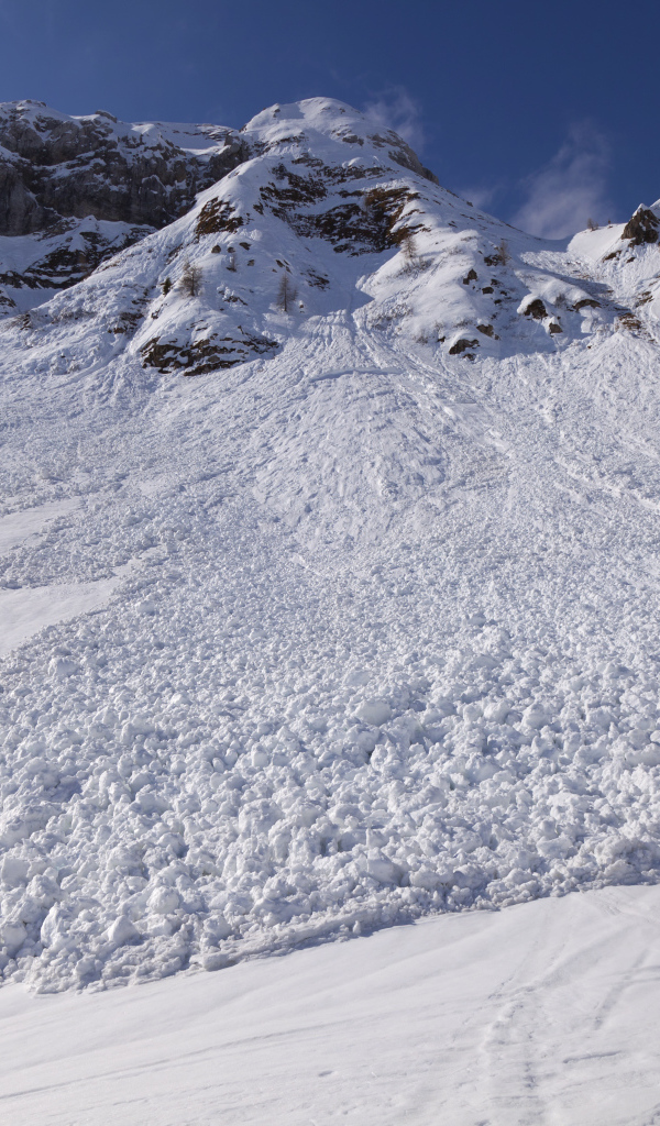 Белая лавина сходит с гор солнечным днем