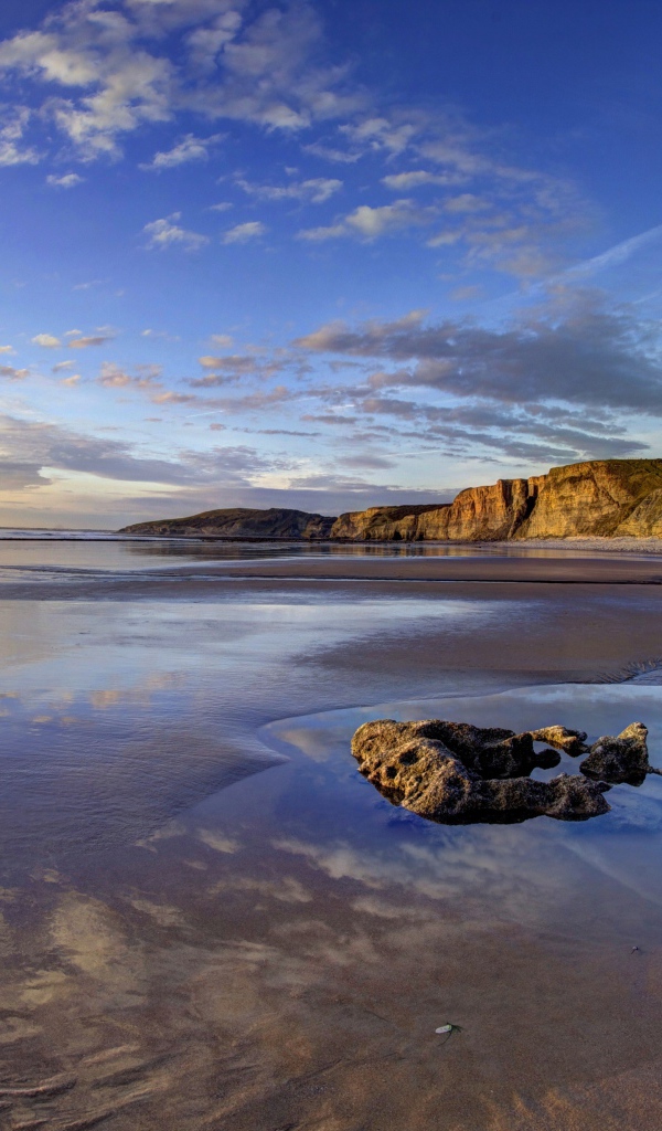 Мокрый морской берег со скалами на закате