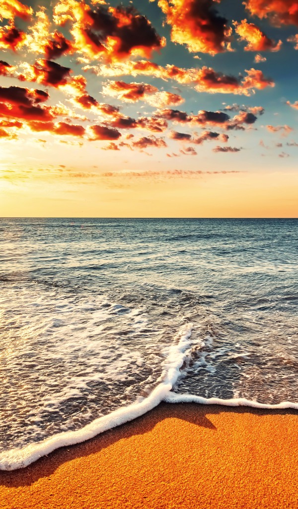 Белая морская пена на оранжевом песке под красивым небом