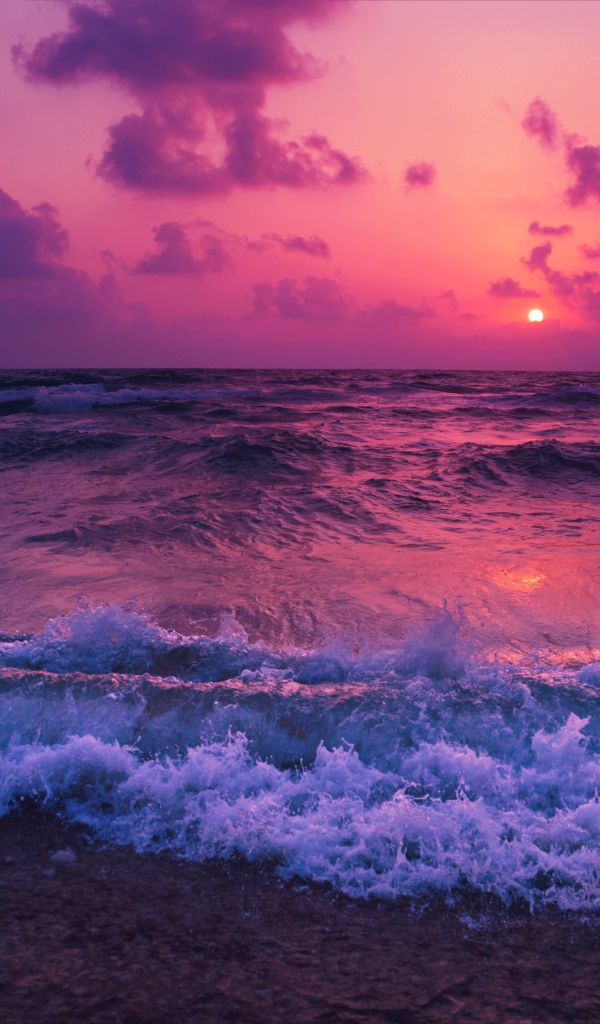 Бушующие волны на берегу на фоне фиолетового закате