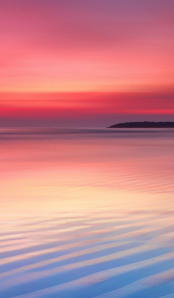 Мокрый белый песок на берегу океана на закате