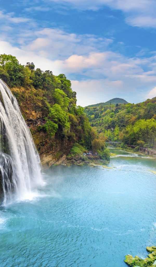 Быстрый водопад стекает с зеленых гор в реку
