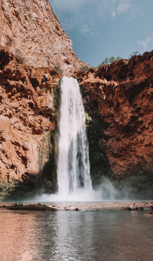 Водопад стекает со скалы в озеро 