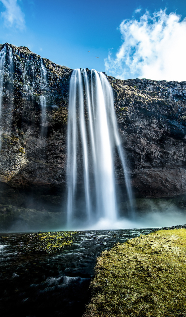 Водопад стекает с гор на фоне голубого неба