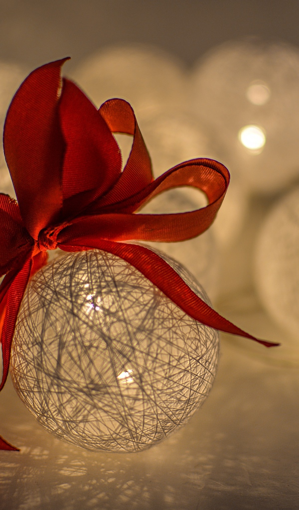 Красивый елочный шар с белых нитей с красным бантом