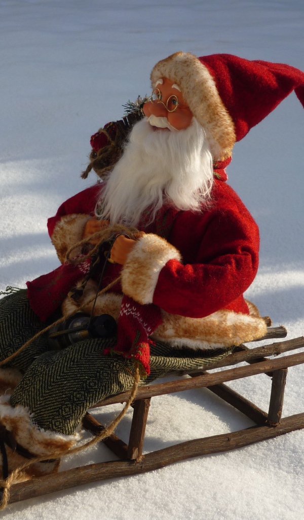 Игрушка деда Мороза на санках стоит на снегу