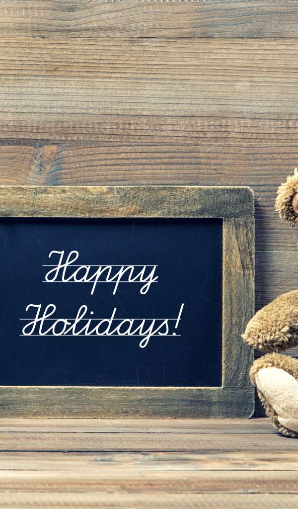 Игрушечный медвежонок Тедди в новогоднем колпаке на деревянном фоне с рамкой