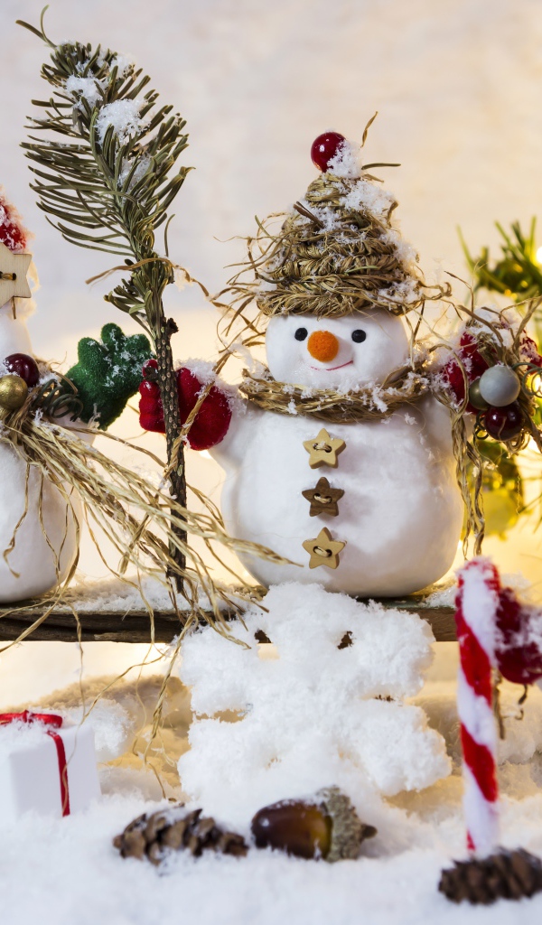 Три снеговика на снегу у искусственной елки на Новый год 