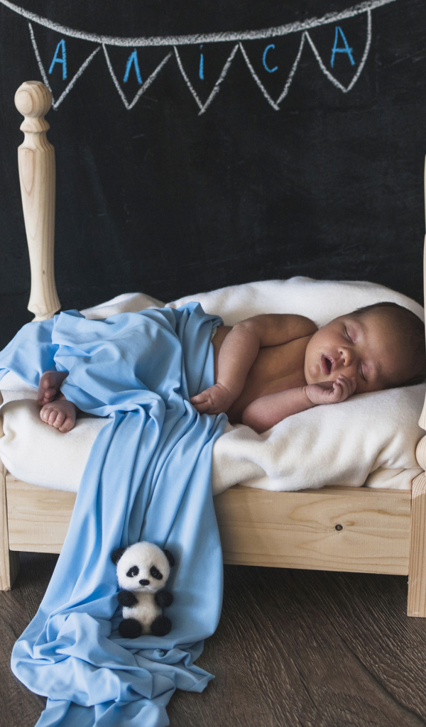 Грудной ребенок спит на деревянной кровати