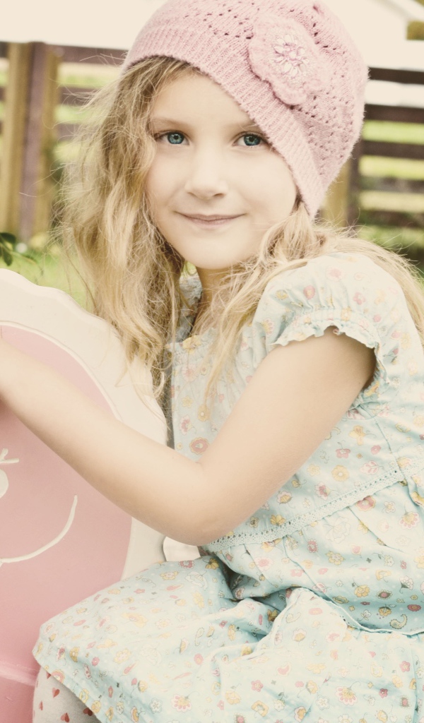 Девочка в платье сидит на деревянной лошади