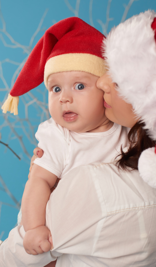 Маленький ребенок в новогоднем костюме на руках у мамы