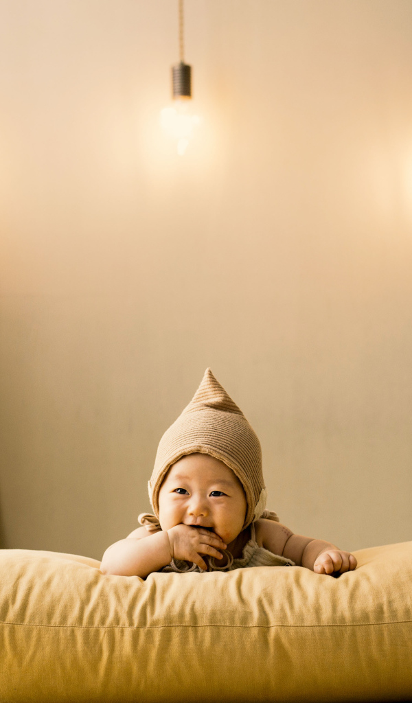 Маленький ребенок лежит на подушке под лампами