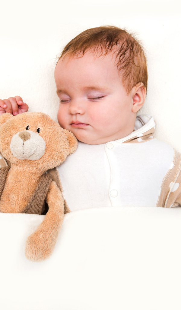 Грудной ребенок спит с плюшевым мишкой на белом фоне