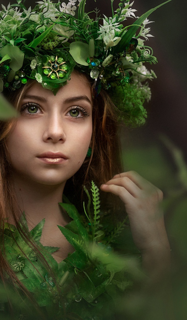 Красивая голубоглазая девочка с венком на голове у дерева