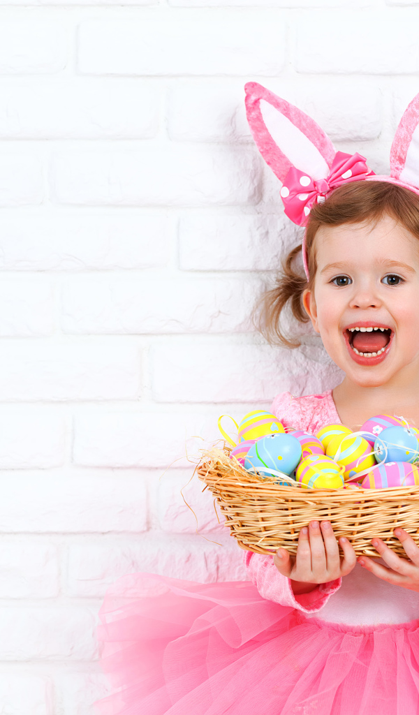 Красивая маленькая девочка в костюме с корзиной крашеных яиц 