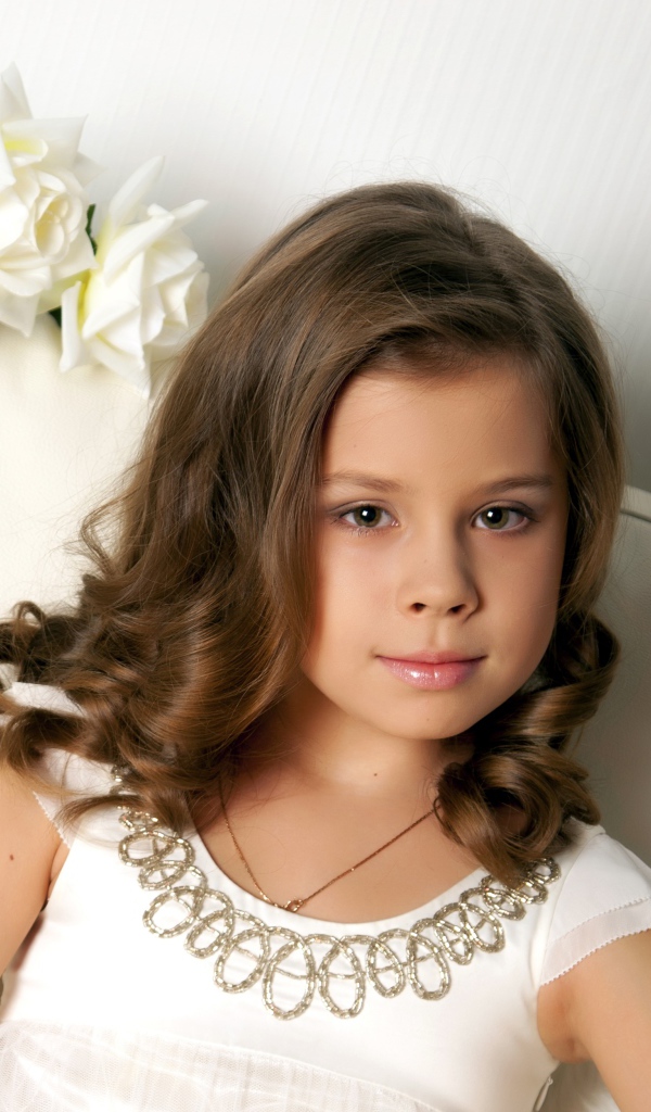 Красивая маленькая девочка сидит в кресле