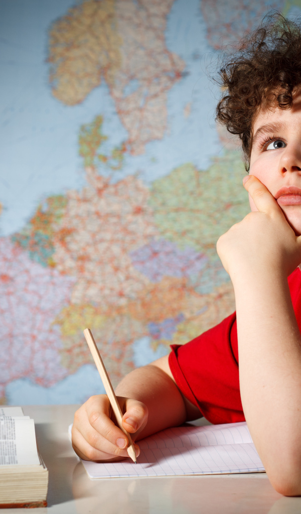 Мальчик ученик делает уроки за столом 